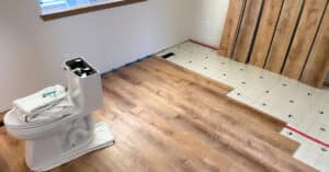 Bathroom remodel: laminate planks mid-install, toilet disconnected and set on towels.